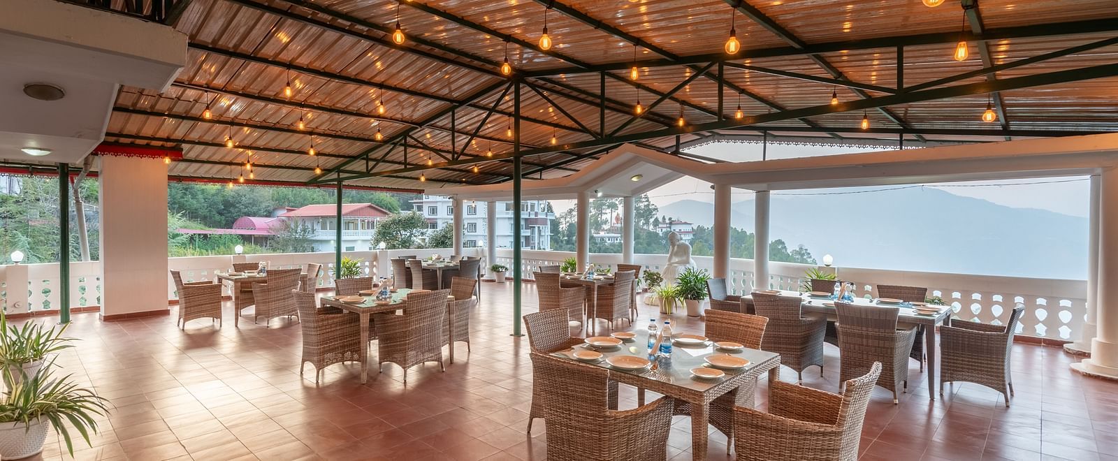 Covered terrace at DLS Tehri Club Resort with tables and chairs, perfect for enjoying the views.